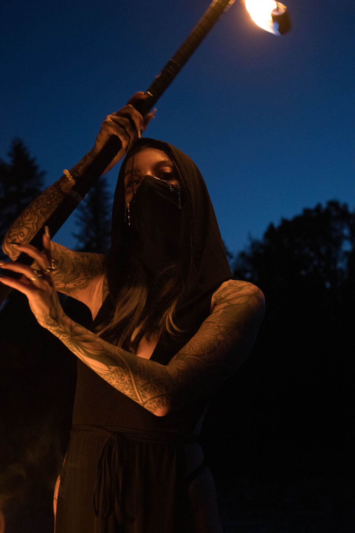 Masked performer holding a staff against a deep blue sky