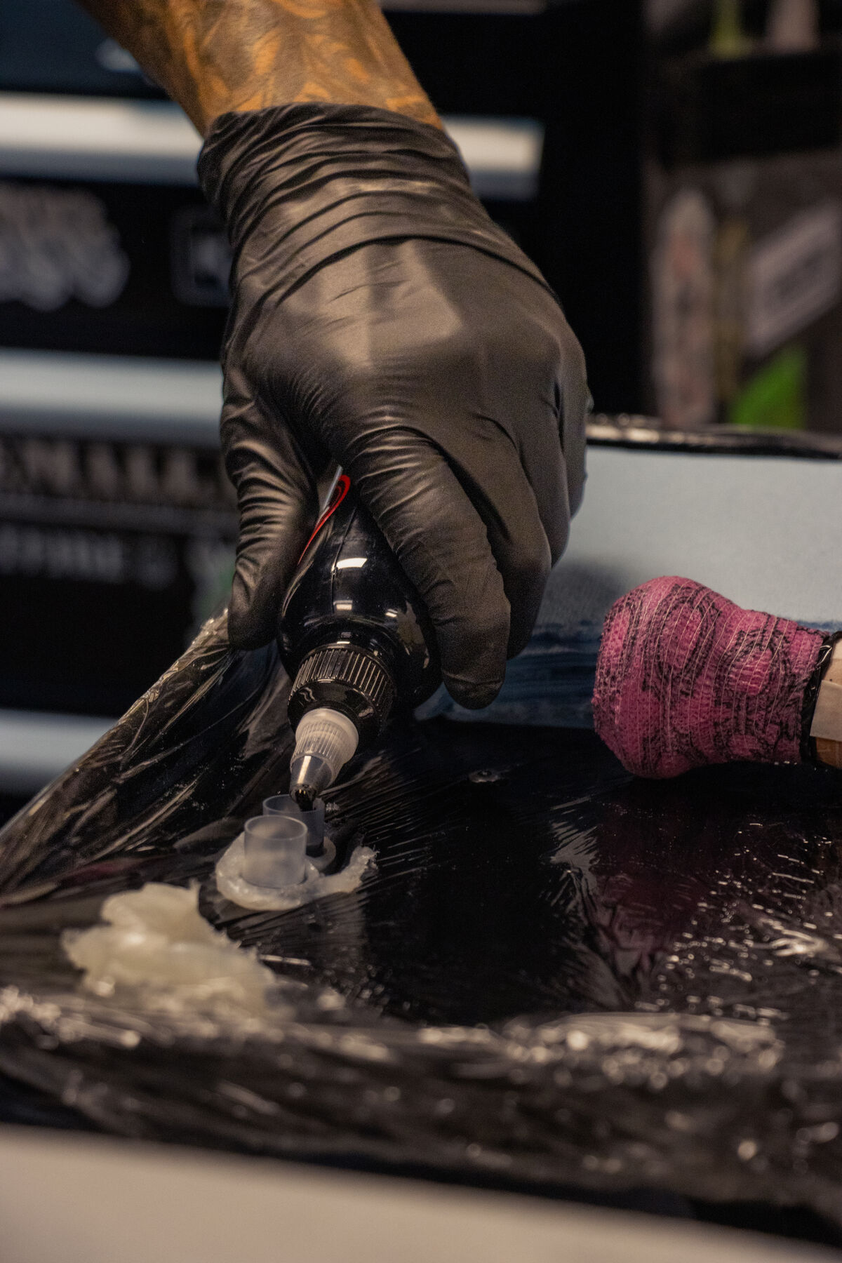 Gloved hand dipping a tattoo machine into ink