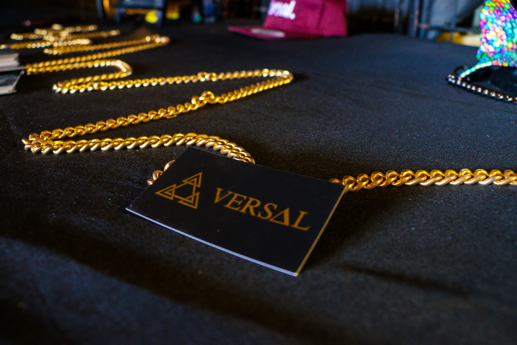 Gold chains laid on black cloth beside a Versal card